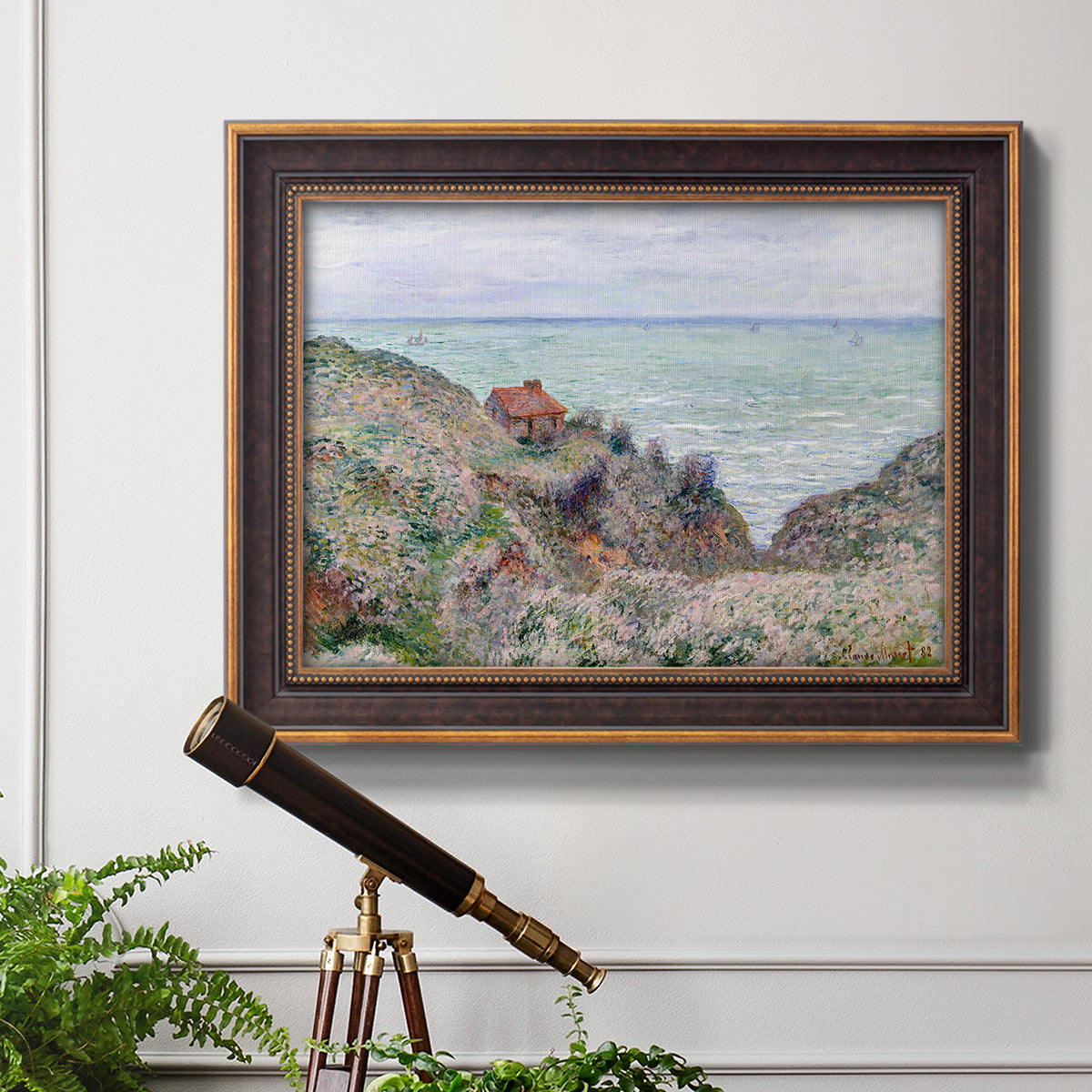 Impressionist coastal watch cabin scene by Claude Monet in an ornate bronzed mahogany wood frame displayed in a light-toned interior setting.