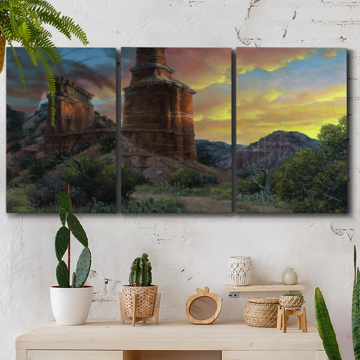 Three-panel canvas wall art featuring dramatic canyon landscape at dusk, displayed in a boho-chic entryway above a console table.