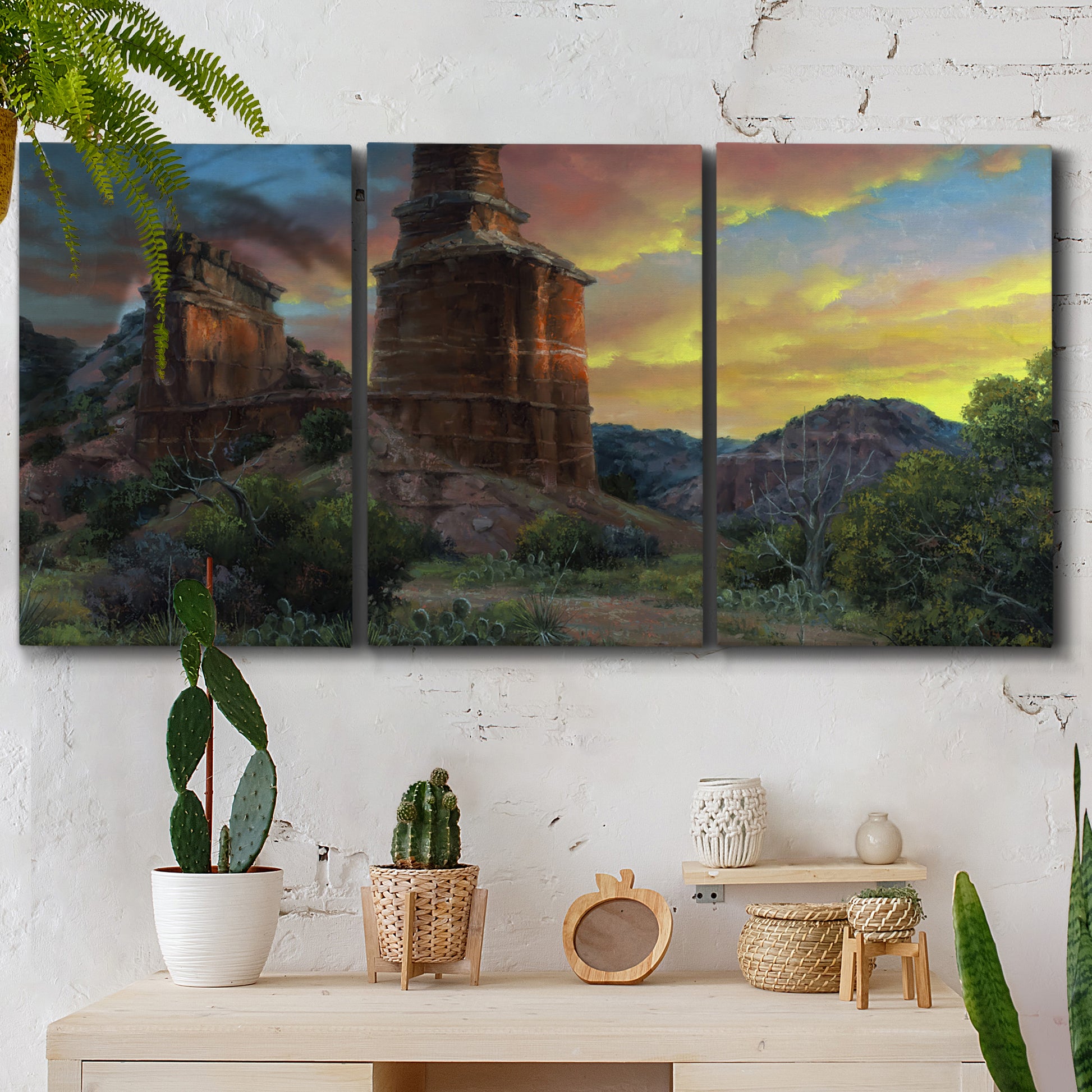 Three-panel canvas wall art featuring dramatic canyon landscape at dusk, displayed in a boho-chic entryway above a console table.