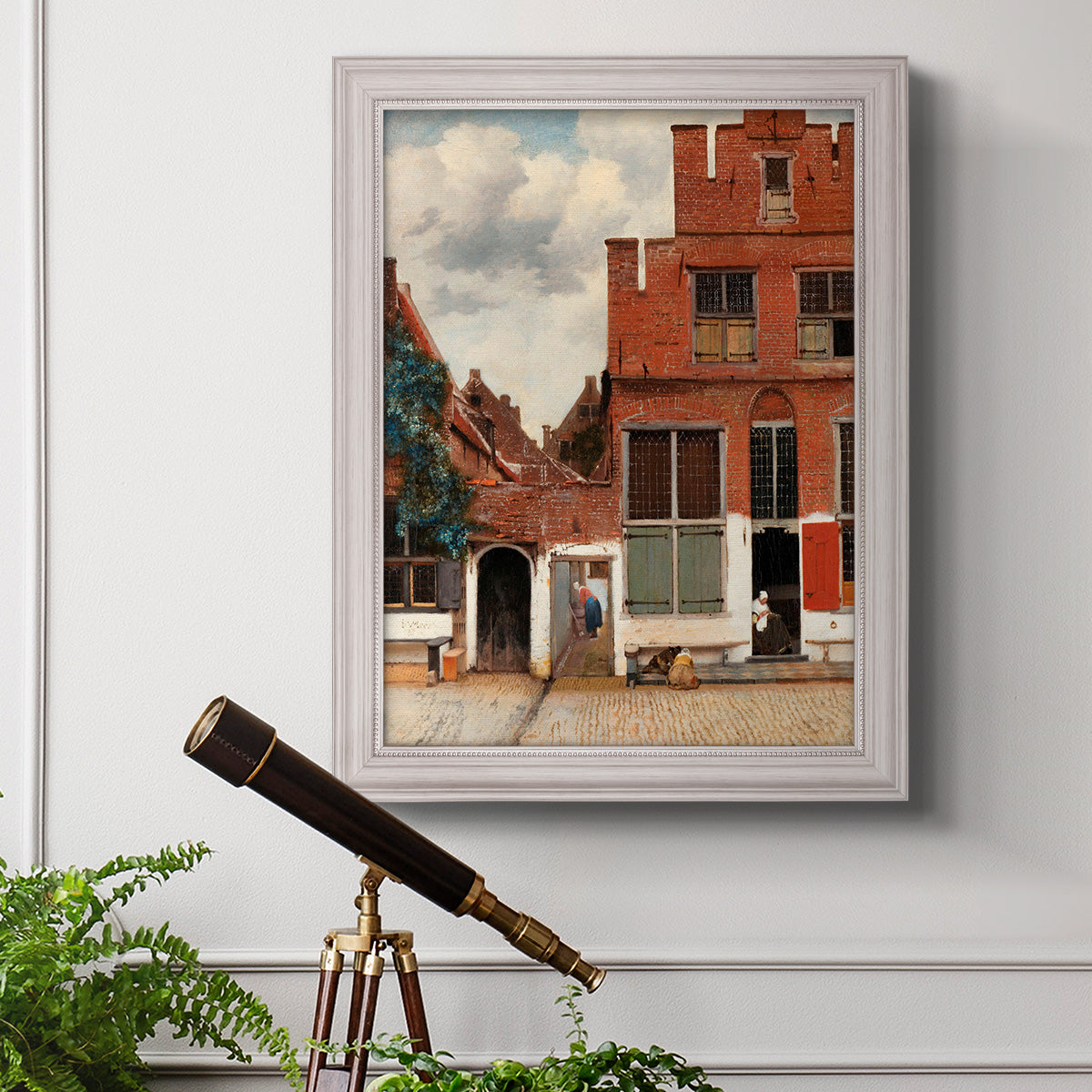 Realist city street scene by Johannes Vermeer in an ornate weathered white frame displayed in a light-toned interior setting.