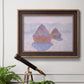 Impressionist winter haystack scene with sunlight by Claude Monet in an ornate bronzed mahogany wood frame displayed in a light-toned interior setting.