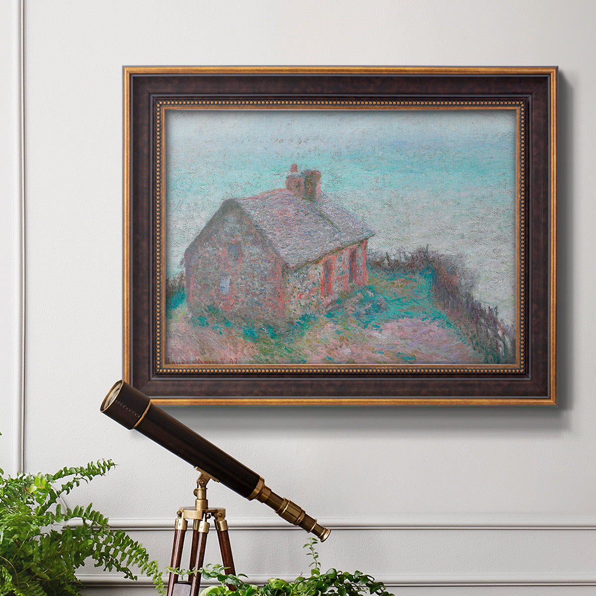 Impressionist coastal building landscape by Claude Monet in an ornate bronzed mahogany wood frame displayed in a light-toned interior setting.