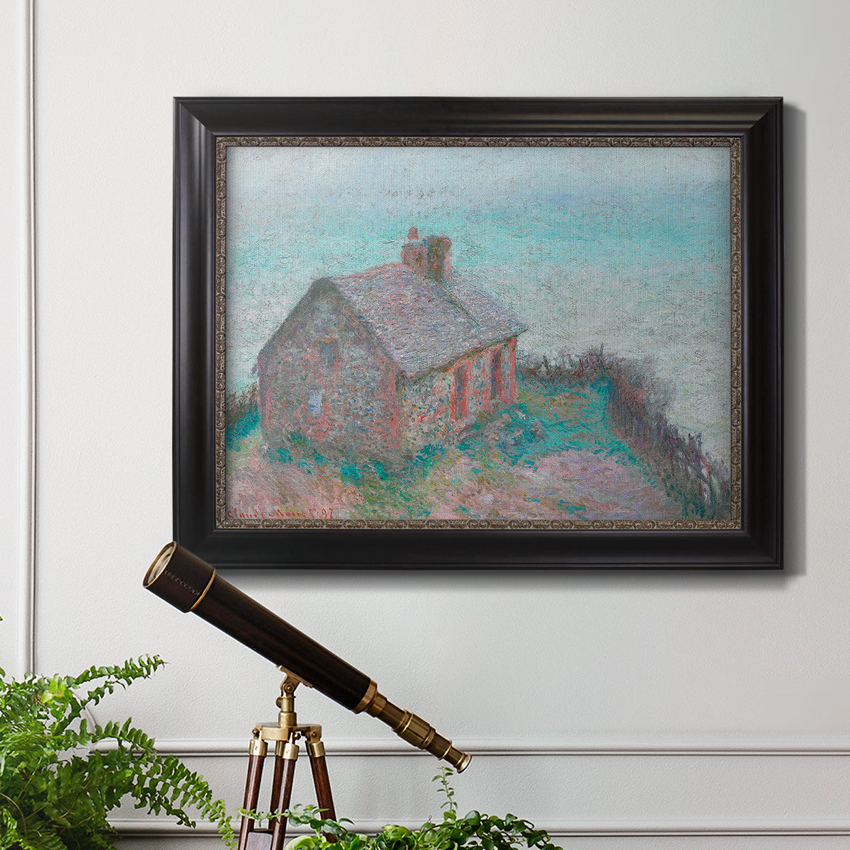 Impressionist coastal building landscape by Claude Monet in an ornate black frame with gilded inner detail displayed in a light-toned interior setting.
