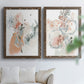 Set of two walnut barnwood framed canvas prints depicting scribbled petals, translucent washes, and drifting stems arranged across two complementary compositions above a sofa in a bright living space.