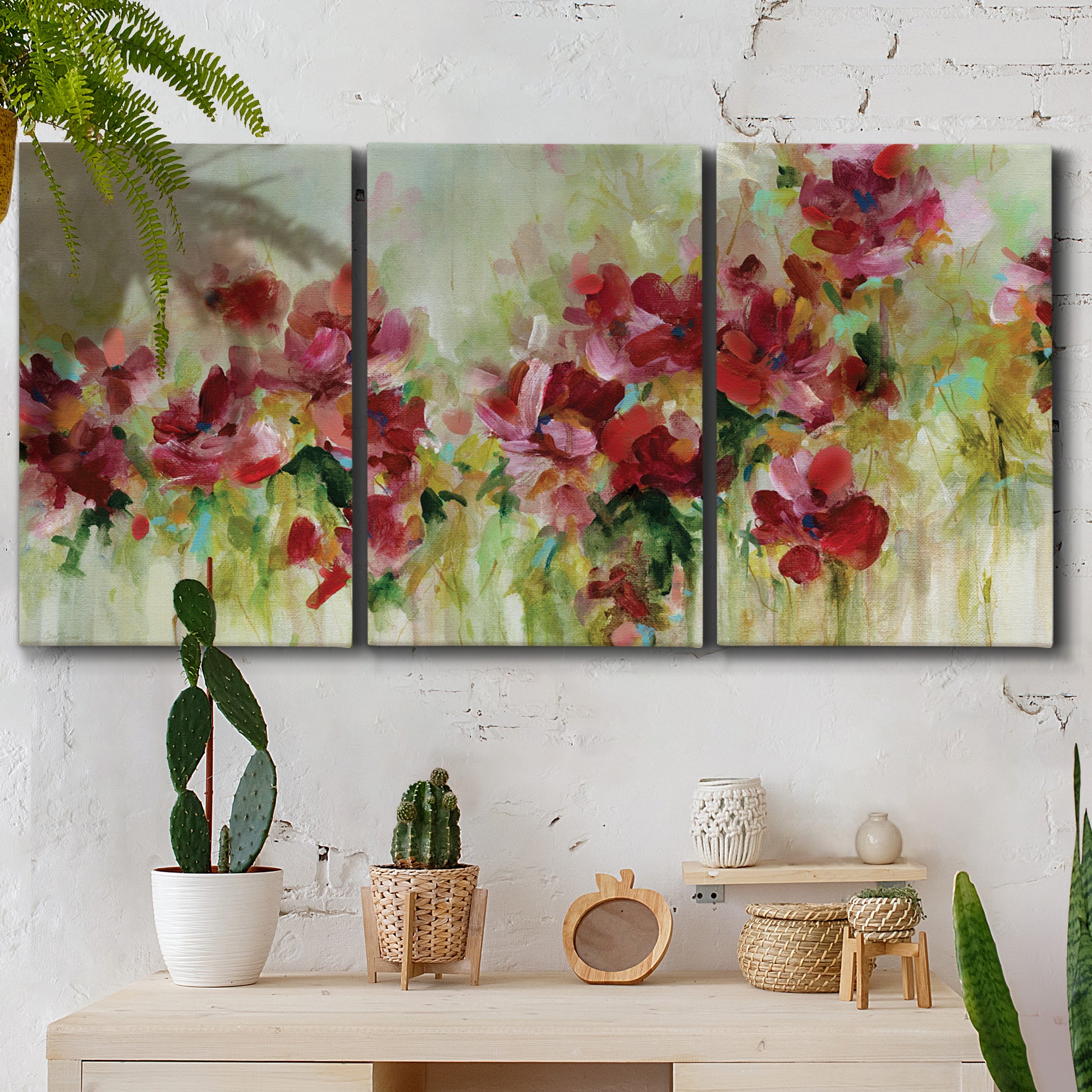 Three-panel canvas wall art featuring colorful floral garden composition, displayed in a boho-chic entryway above a console table.