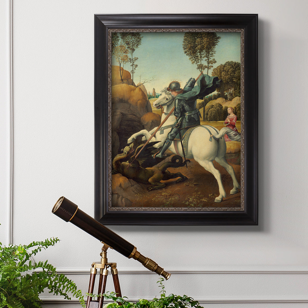 Religious painting of Saint George slaying the dragon by Raphael in an ornate black frame with gilded inner detail displayed in a light-toned interior setting.