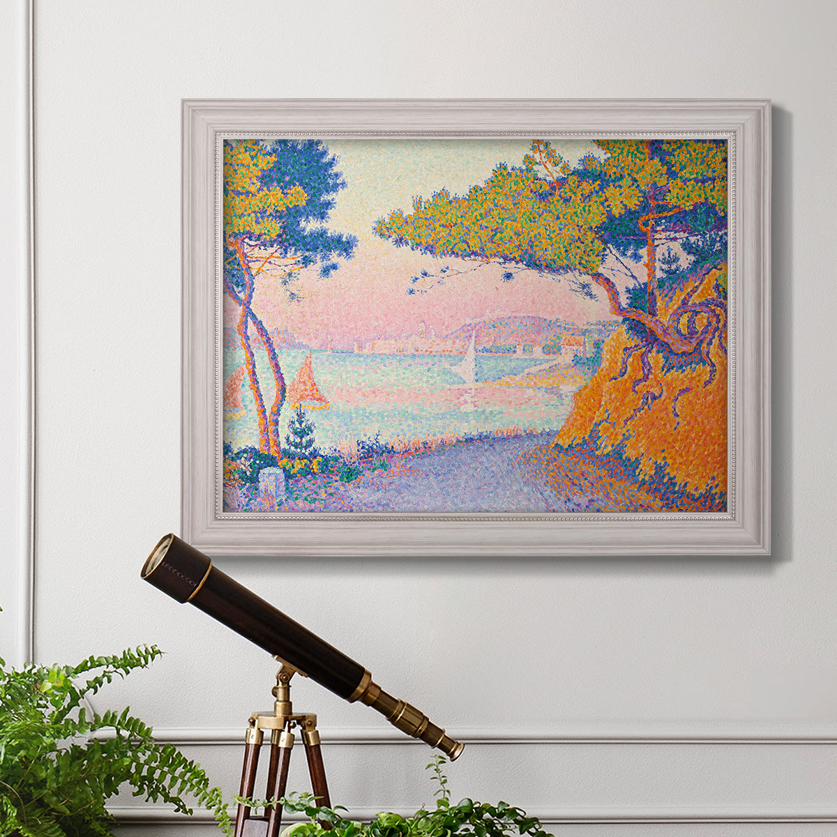 Pointillist coastal seascape by Paul Signac in an ornate weathered white frame displayed in a light-toned interior setting.