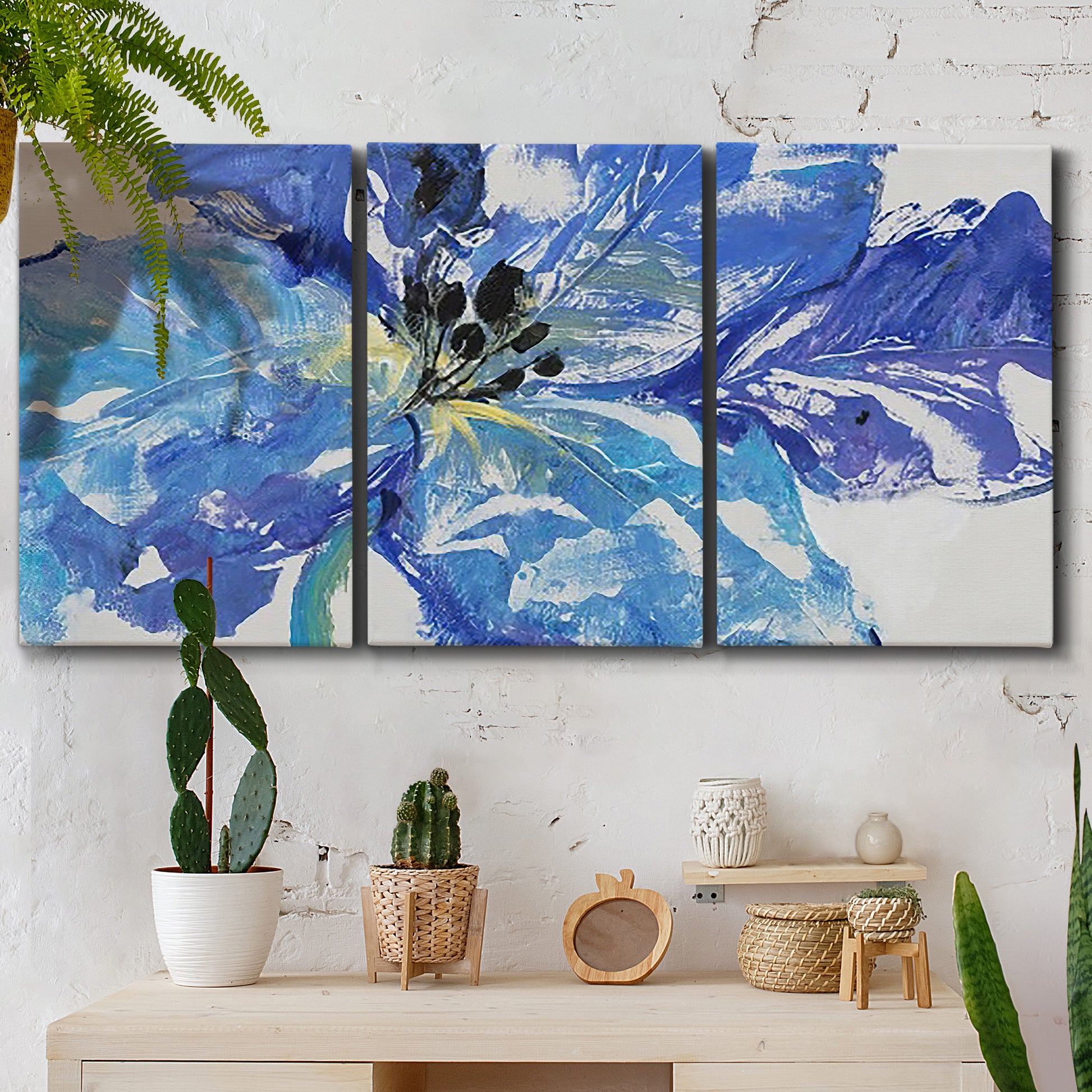 Three-panel canvas wall art featuring blue floral botanical close up, displayed in a boho-chic entryway above a console table.