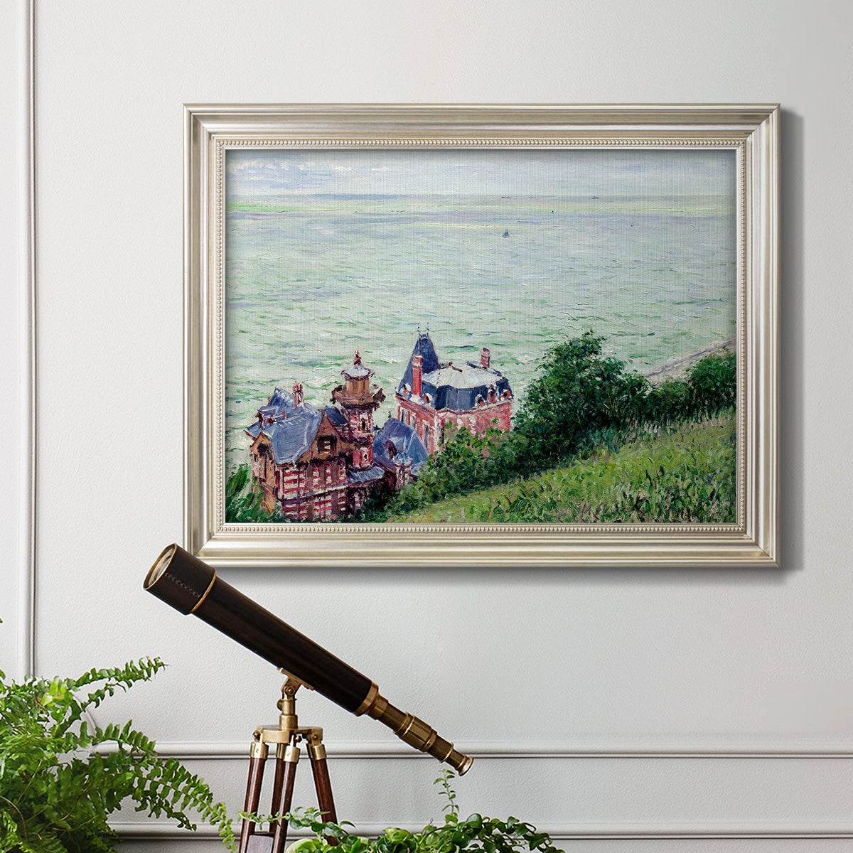 Impressionist coastal villas landscape by Gustave Caillebotte in an ornate champagne frame displayed in a light-toned interior setting.