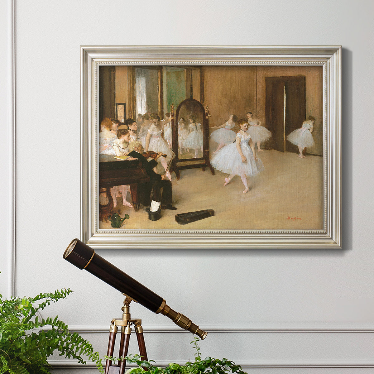 Impressionist dance class interior scene by Edgar Degas in an ornate champagne frame displayed in a light-toned interior setting.