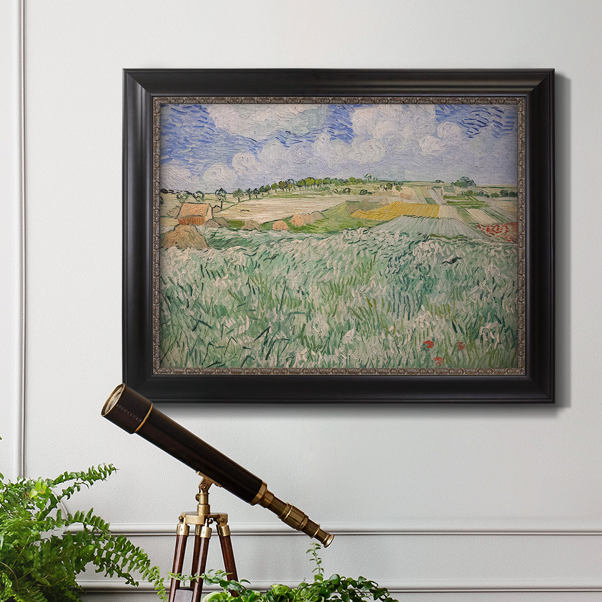 Impressionist countryside landscape near Auvers by Vincent van Gogh in an ornate black frame with gilded inner detail displayed in a light-toned interior setting.