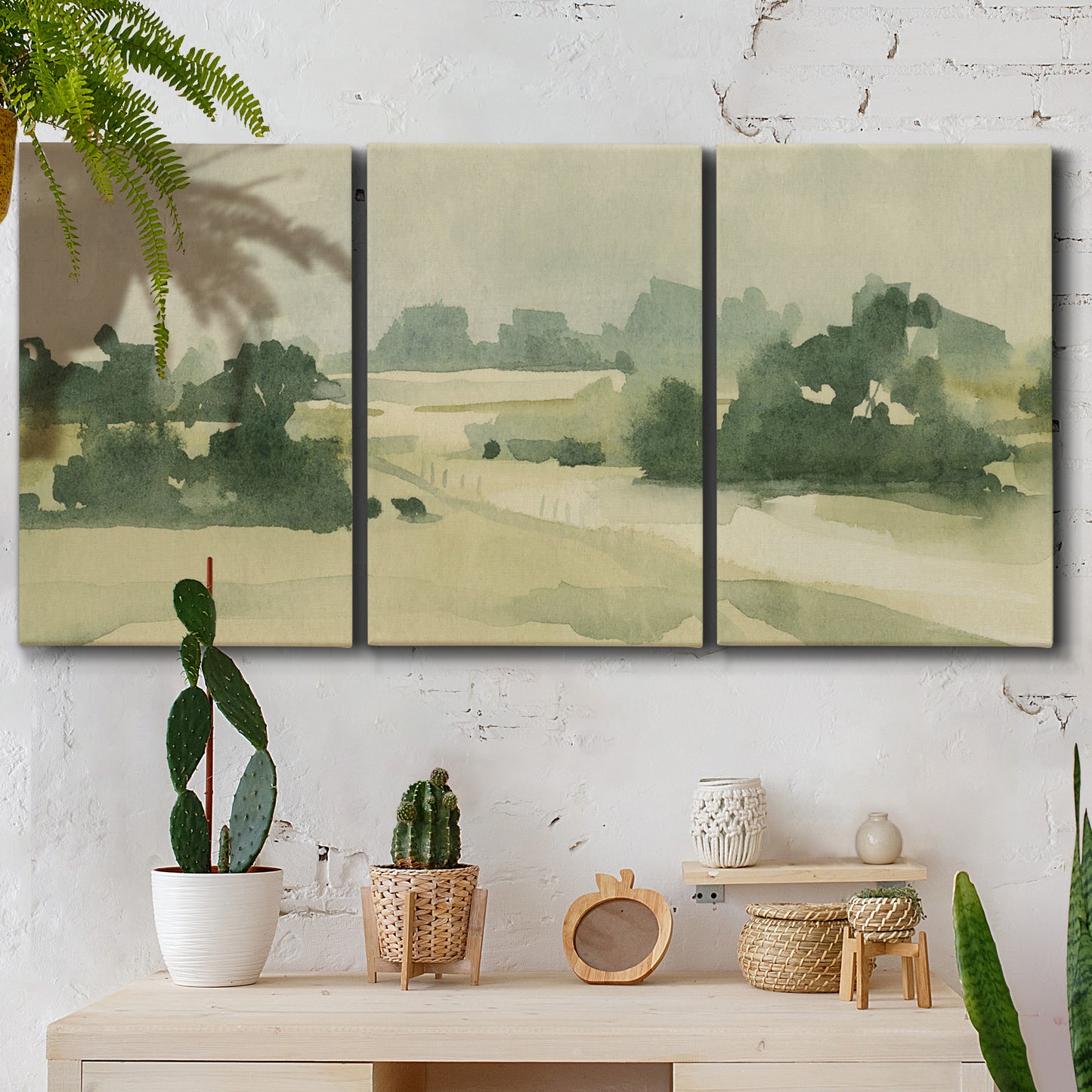 Three-panel canvas wall art featuring pasture landscape in soft watercolor, displayed in a boho-chic entryway above a console table.