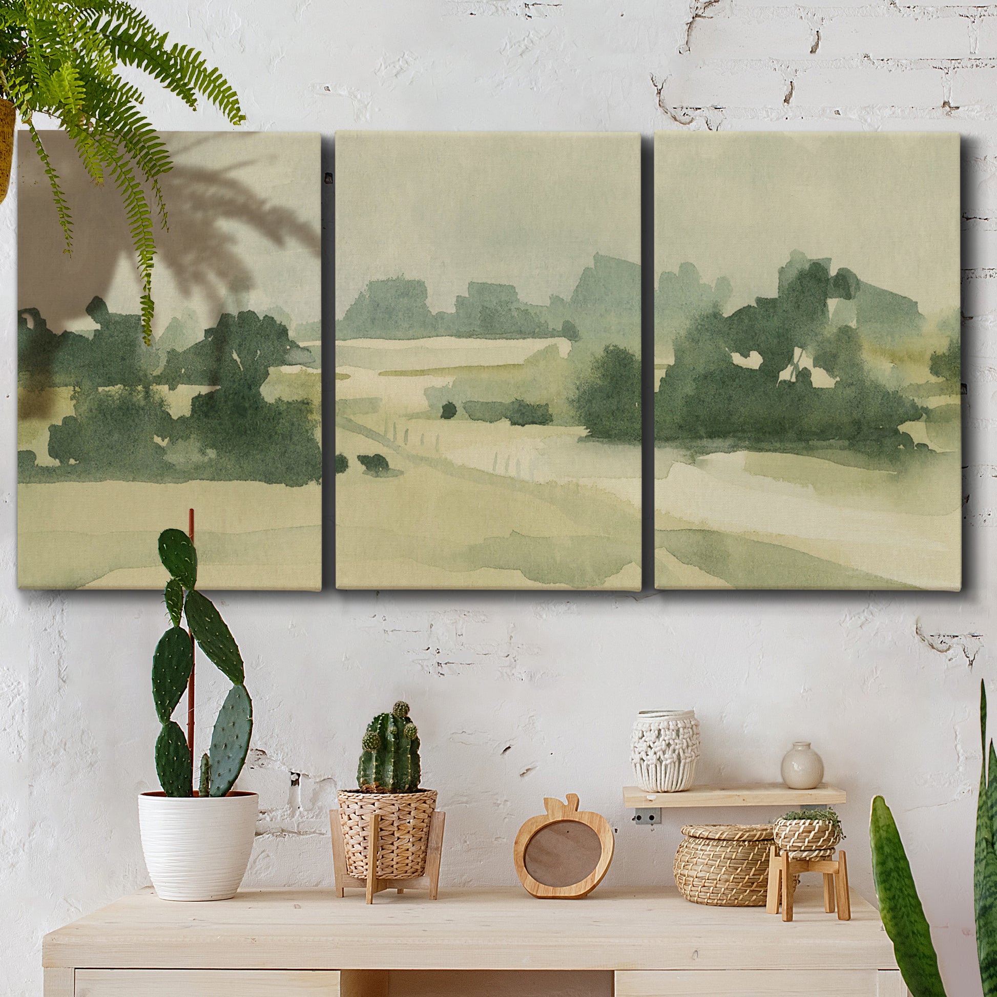 Three-panel canvas wall art featuring pasture landscape in soft watercolor, displayed in a boho-chic entryway above a console table.