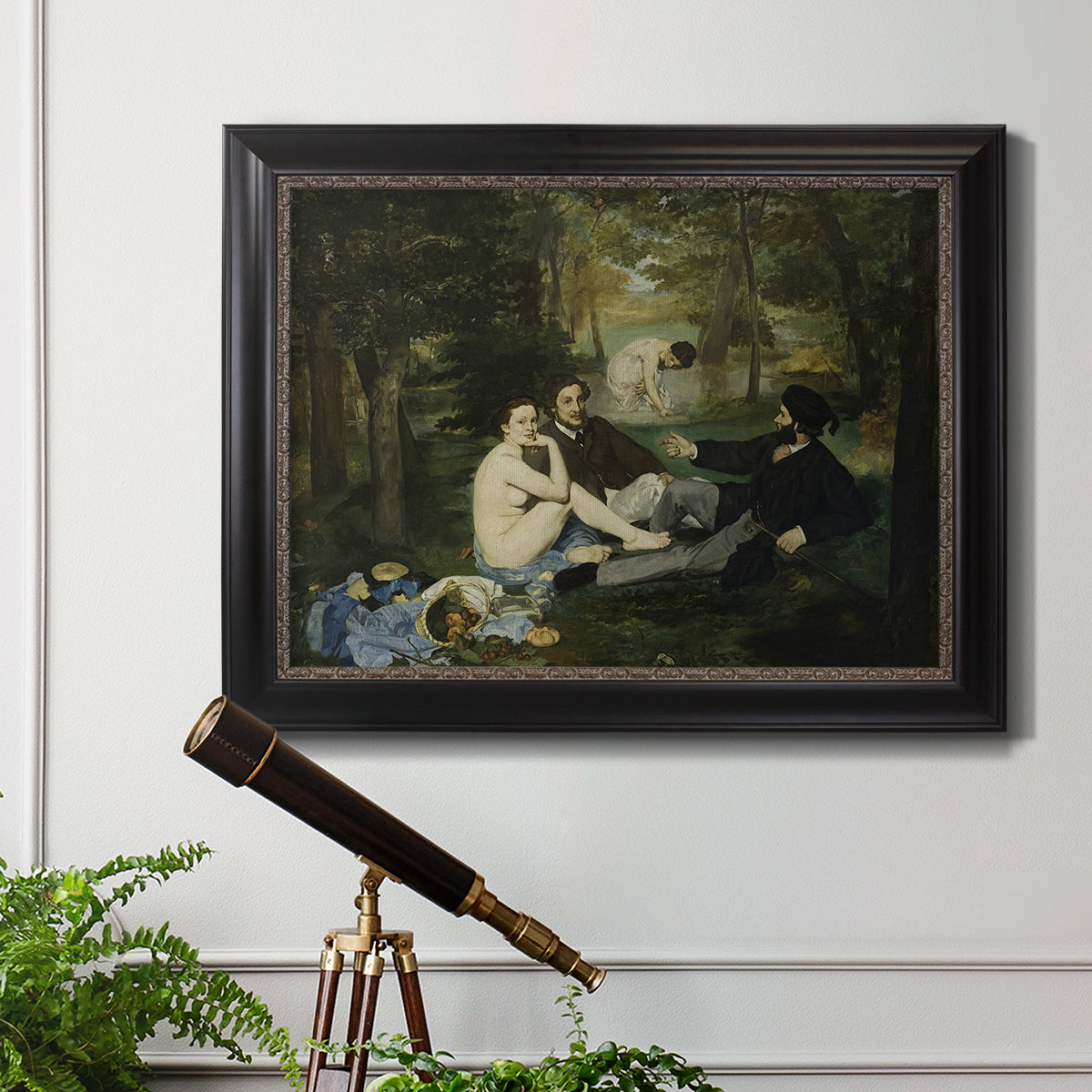 Groundbreaking impressionist picnic scene by Édouard Manet in an ornate black frame with gilded inner detail displayed in a light-toned interior setting.