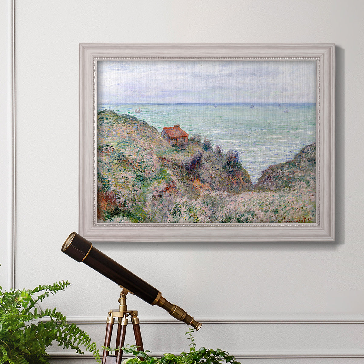 Impressionist coastal watch cabin scene by Claude Monet in an ornate weathered white frame displayed in a light-toned interior setting.