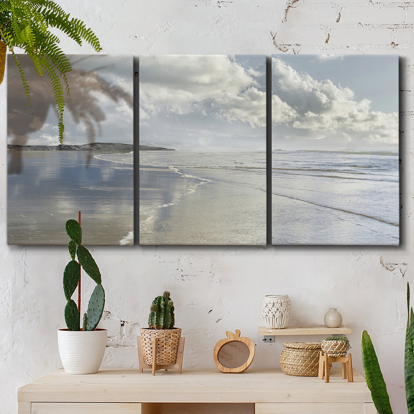 Three-panel canvas wall art featuring endless beach meeting ocean horizon, displayed in a boho-chic entryway above a console table.