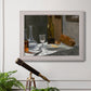 Impressionist still life with wine and bread by Claude Monet in an ornate weathered white frame displayed in a light-toned interior setting.