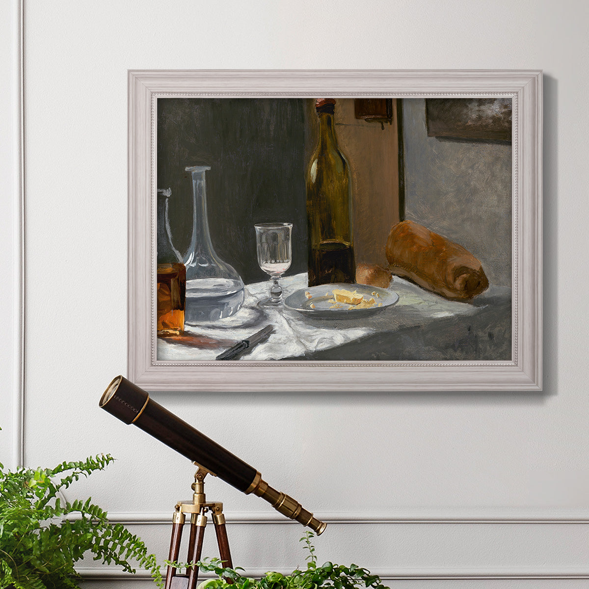 Impressionist still life with wine and bread by Claude Monet in an ornate weathered white frame displayed in a light-toned interior setting.