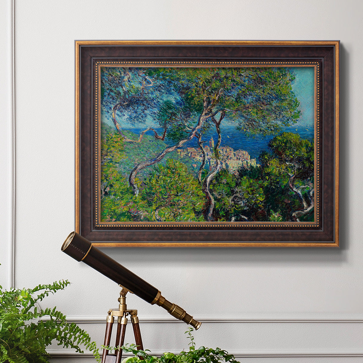Impressionist Mediterranean coastal landscape by Claude Monet in an ornate bronzed mahogany wood frame displayed in a light-toned interior setting.