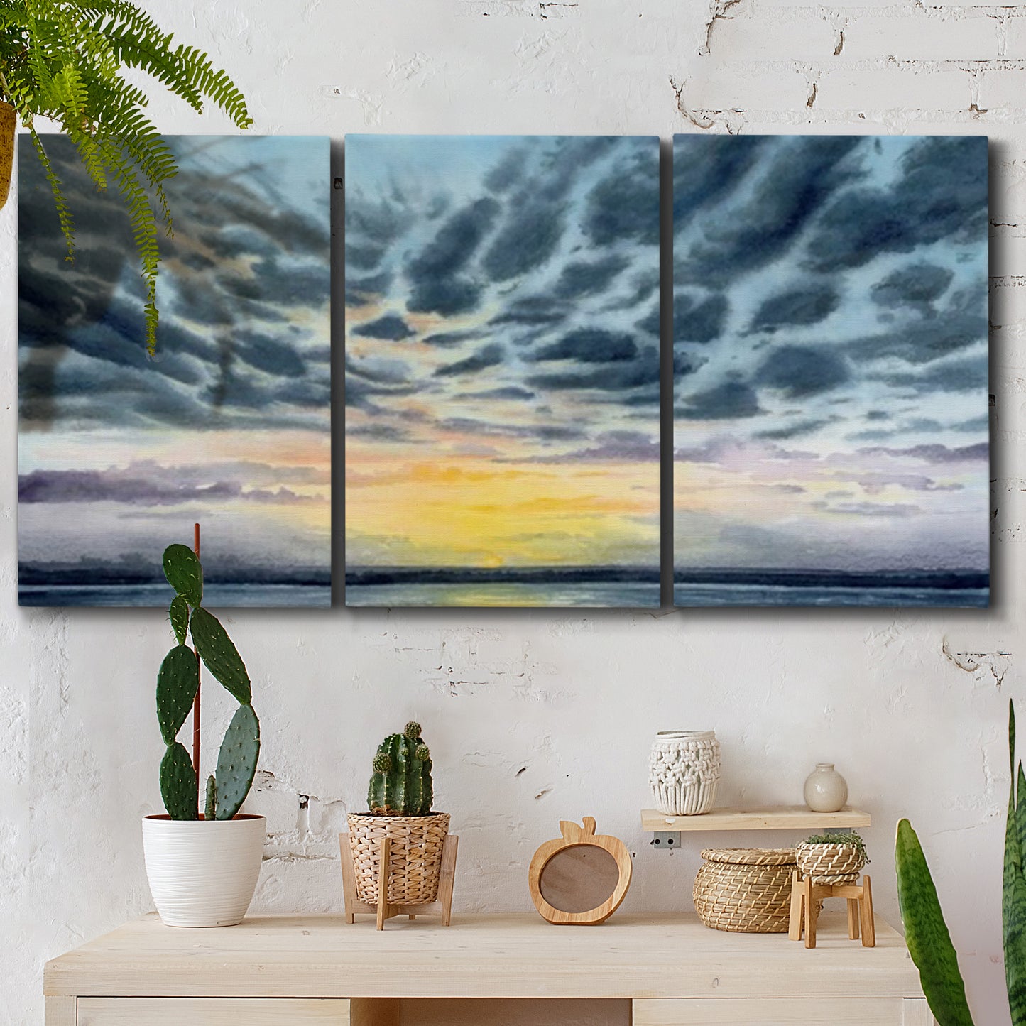 Three-panel canvas wall art featuring tropical coastal sunset over water, displayed in a boho-chic entryway above a console table.