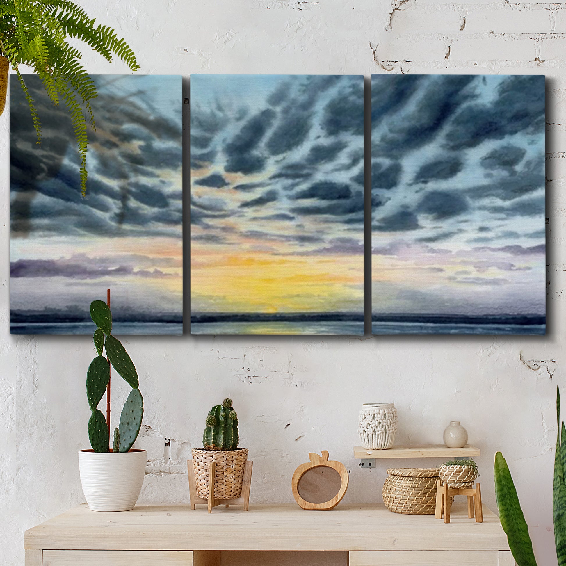 Three-panel canvas wall art featuring tropical coastal sunset over water, displayed in a boho-chic entryway above a console table.