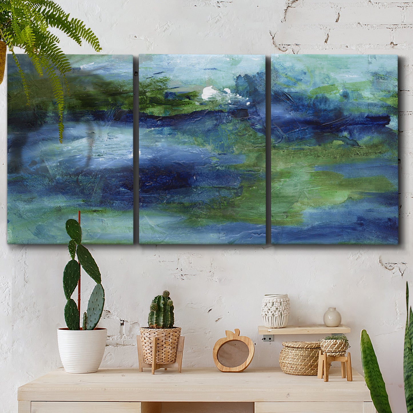 Three-panel canvas wall art featuring flowing blue abstract watercolor, displayed in a boho-chic entryway above a console table.