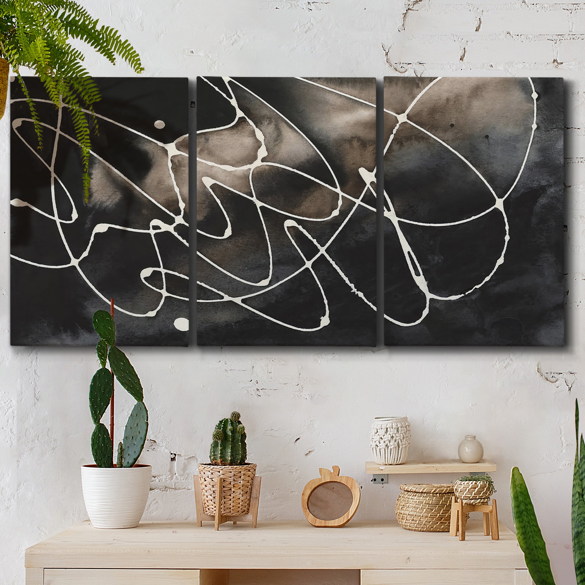 Three-panel canvas wall art featuring dark swirling abstract motion, displayed in a boho-chic entryway above a console table.