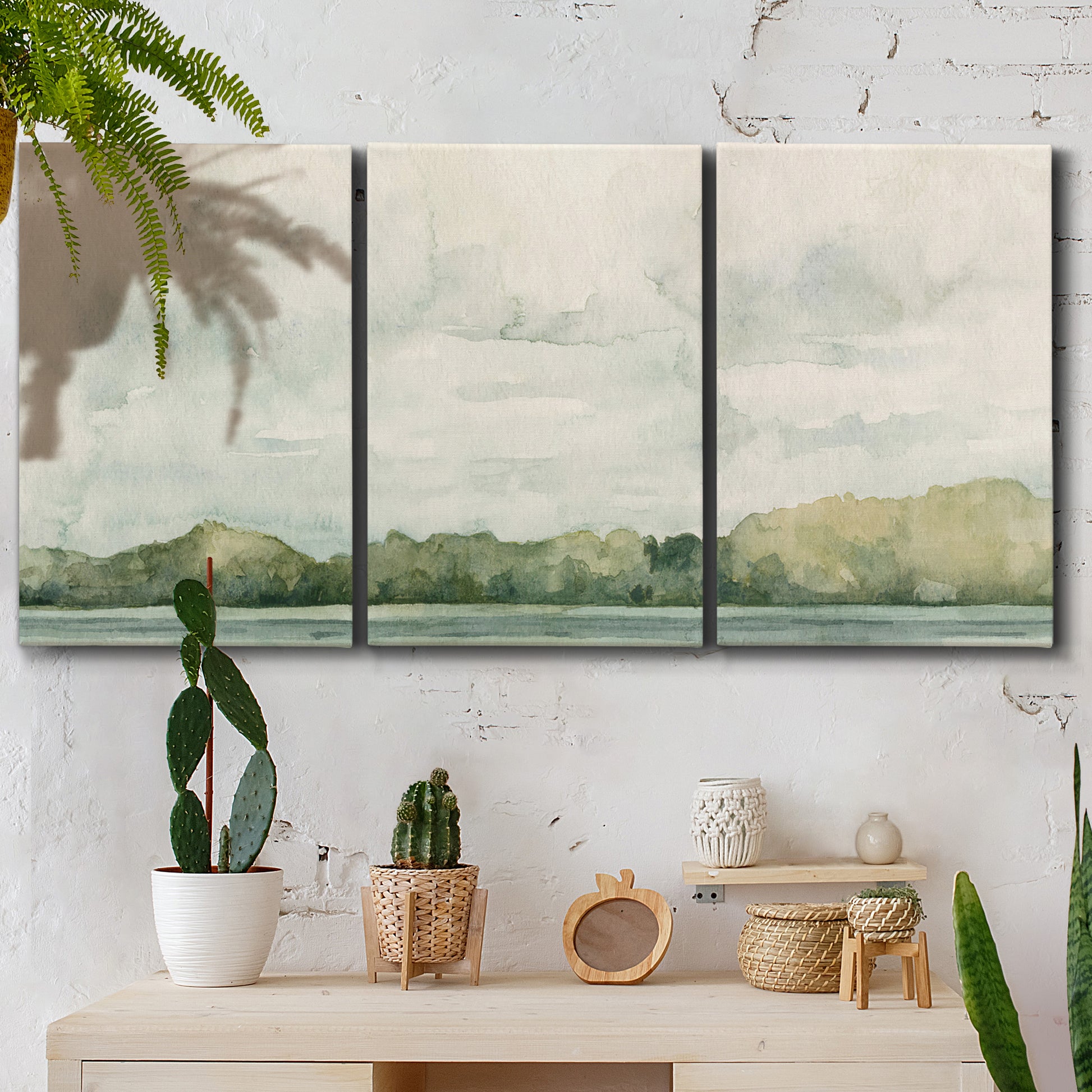 Three-panel canvas wall art featuring riverbank landscape with trees, displayed in a boho-chic entryway above a console table.