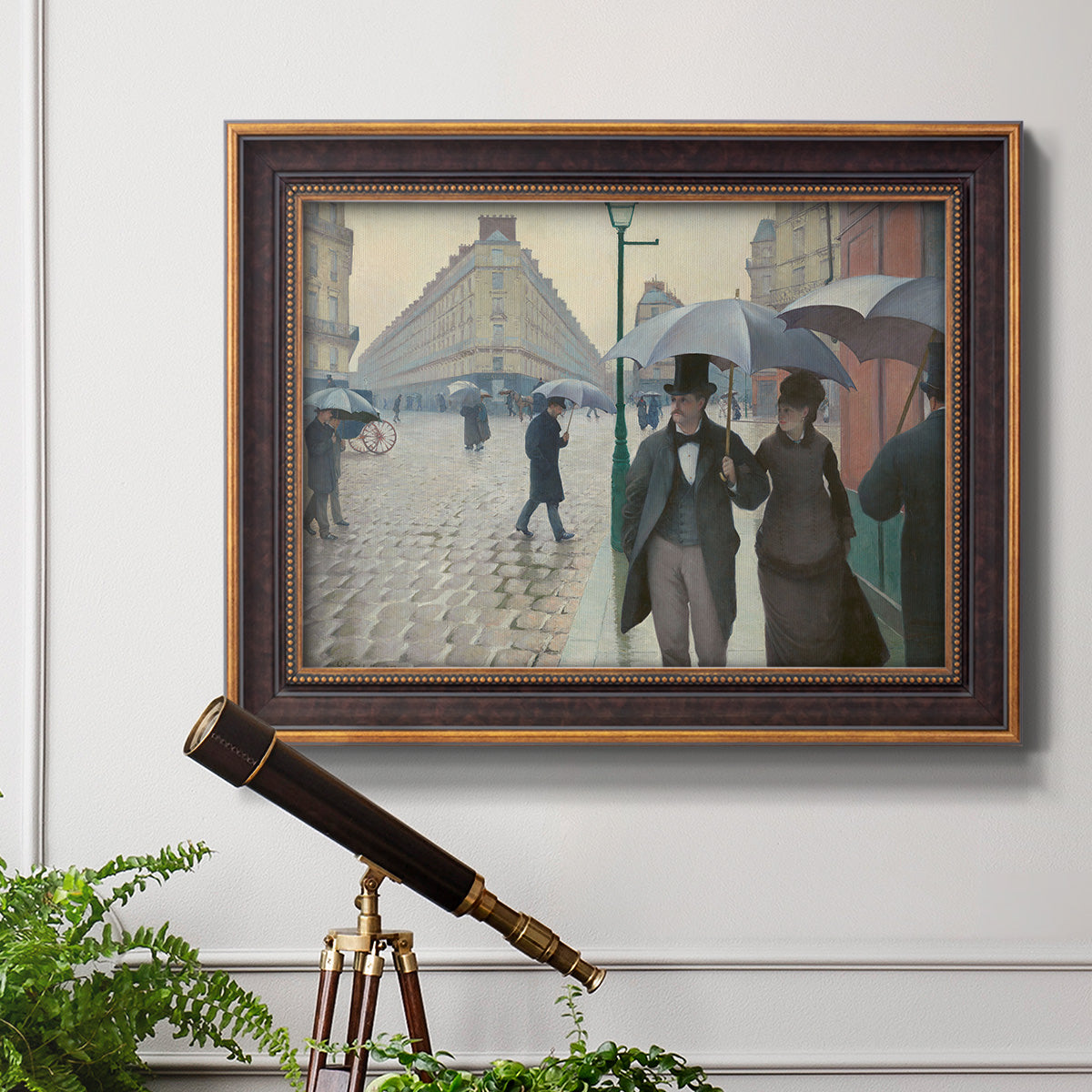Impressionist urban street scene in the rain by Gustave Caillebotte in an ornate bronzed mahogany wood frame displayed in a light-toned interior setting.