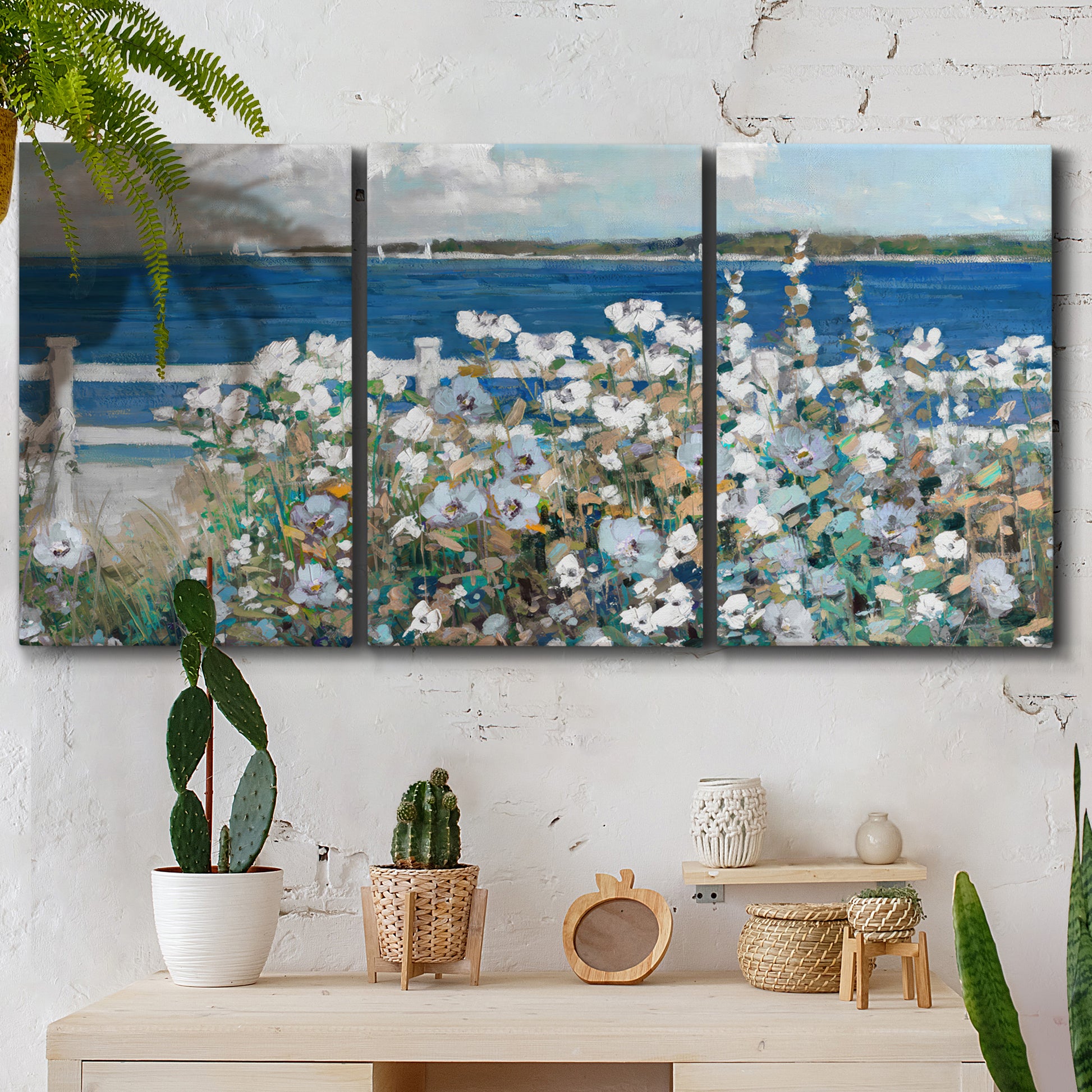 Three-panel canvas wall art featuring coastal garden overlooking bay, displayed in a boho-chic entryway above a console table.