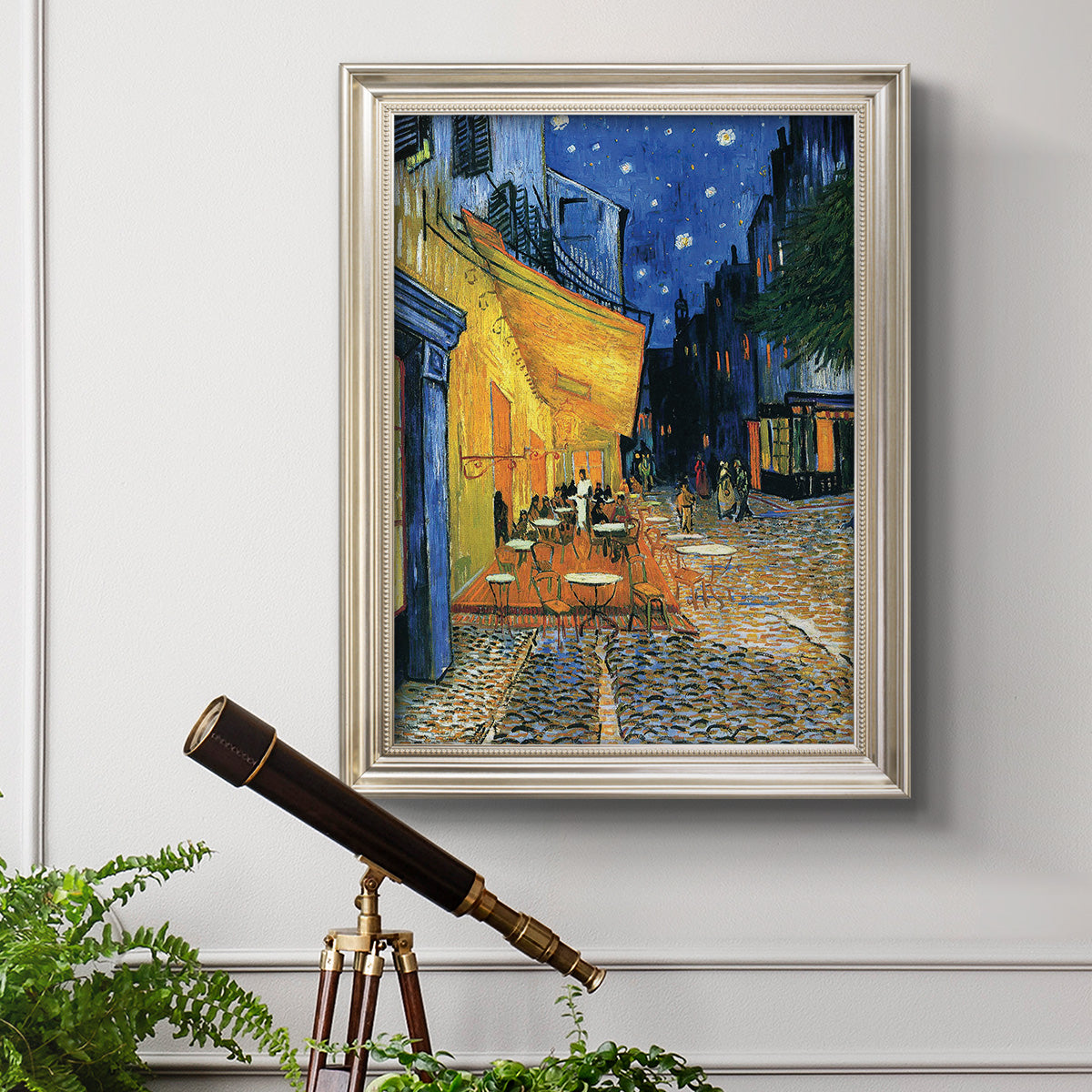 Impressionist night café street scene by Vincent van Gogh in an ornate champagne frame displayed in a light-toned interior setting.