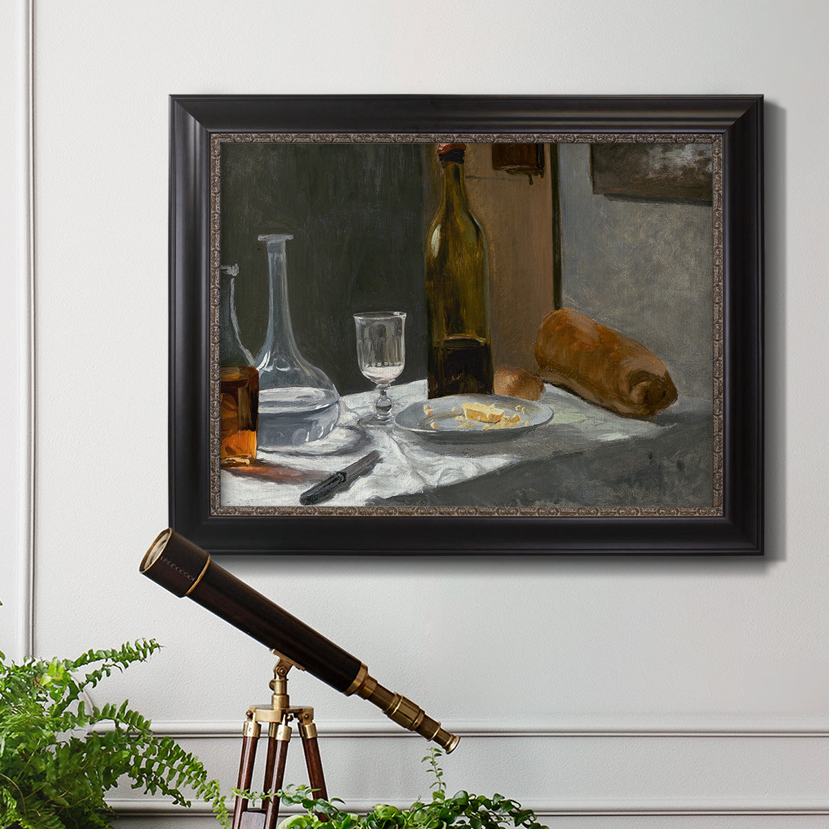 Impressionist still life with wine and bread by Claude Monet in an ornate black frame with gilded inner detail displayed in a light-toned interior setting.