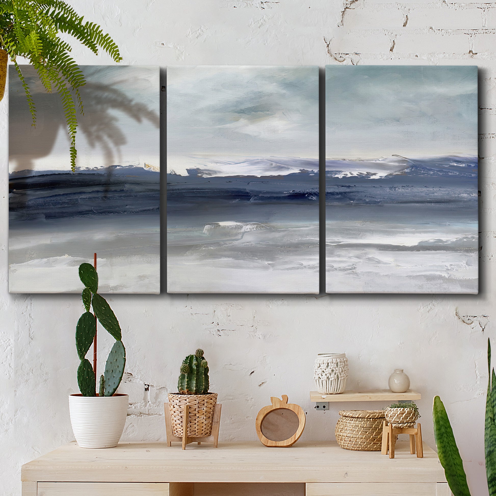Three-panel canvas wall art featuring abstract coastal tones and movement, displayed in a boho-chic entryway above a console table.