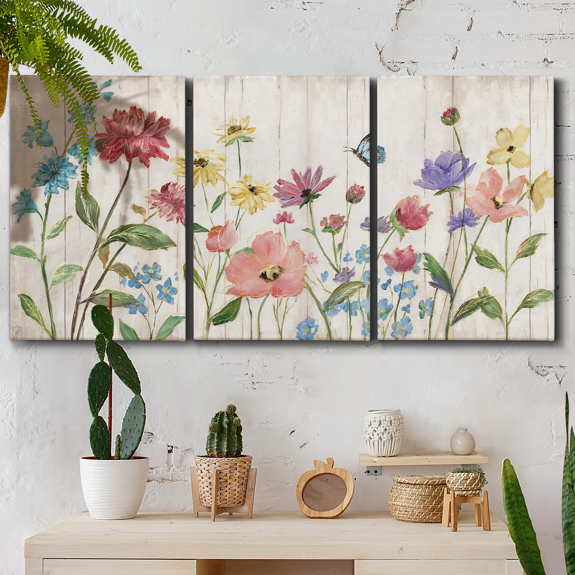 Three-panel canvas wall art featuring delicate wildflower illustration, displayed in a boho-chic entryway above a console table.