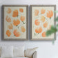 Set of two gray barnwood framed canvas prints depicting soft petals, thin black stems, and warm cream backgrounds arranged across two complementary compositions above a sofa in a bright living space.
