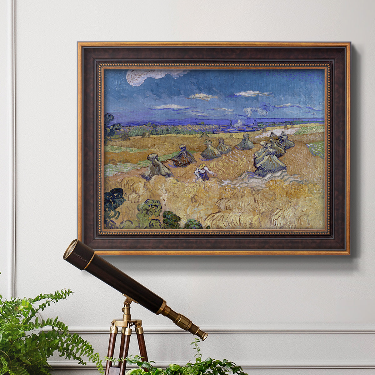 Impressionist wheat harvest scene by Vincent van Gogh in an ornate bronzed mahogany wood frame displayed in a light-toned interior setting.
