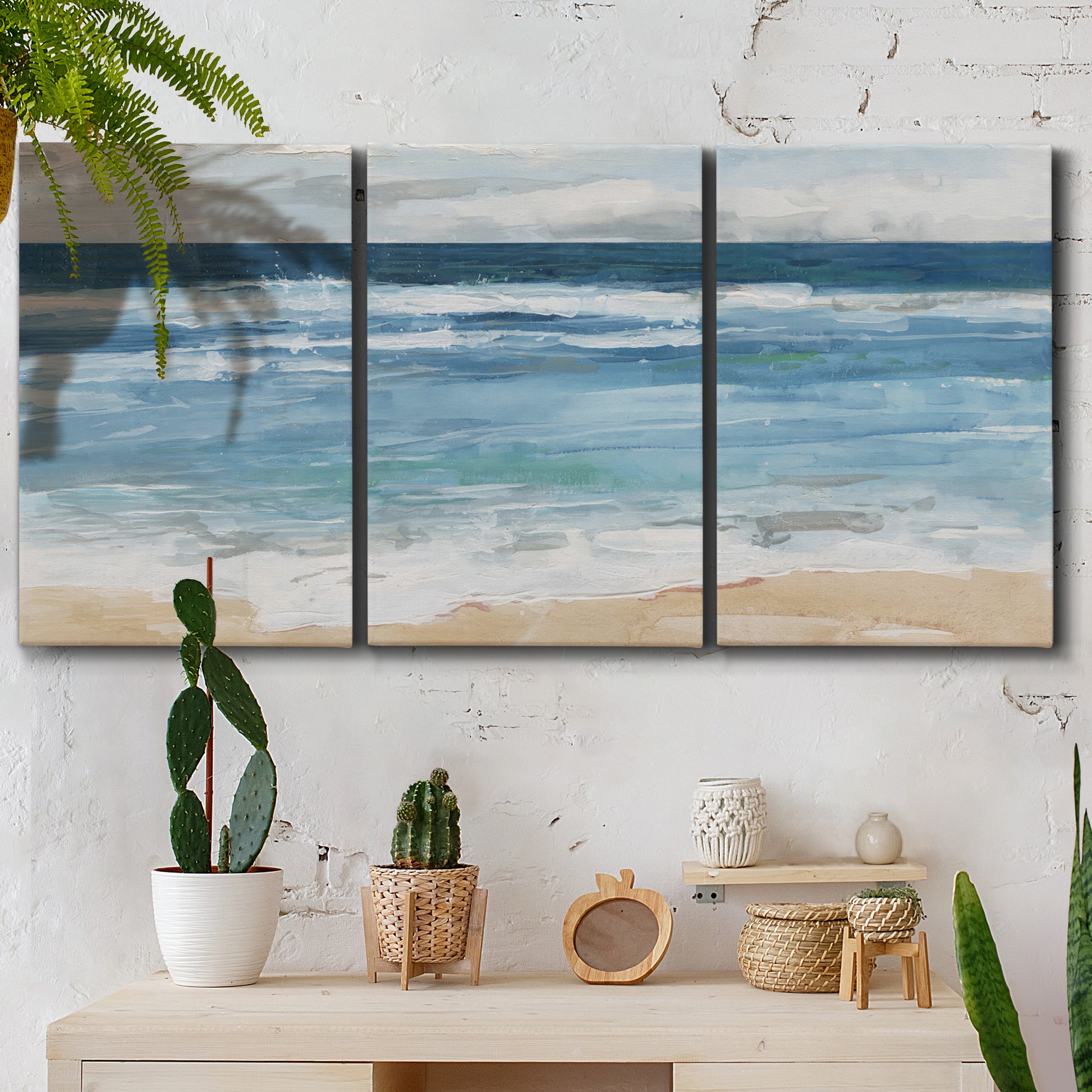 Three-panel canvas wall art featuring rolling ocean waves near shore, displayed in a boho-chic entryway above a console table.