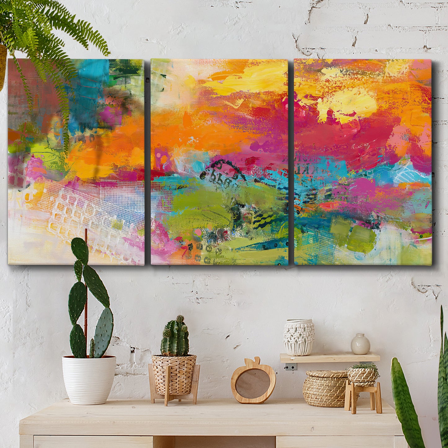 Three-panel canvas wall art featuring expressive abstract sunset tones, displayed in a boho-chic entryway above a console table.