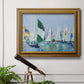 Coastal harbor watercolor painting in an ornate traditional gold frame displayed in a light-toned interior setting.