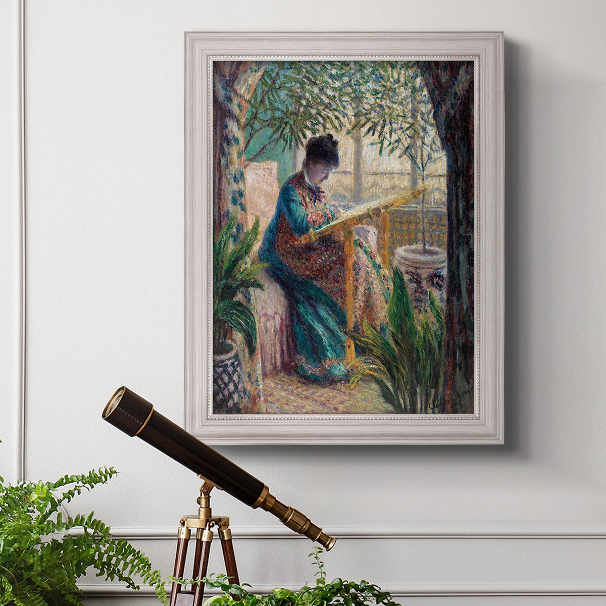 Impressionist portrait of Madame Monet sewing by Claude Monet in an ornate weathered white frame displayed in a light-toned interior setting.