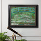 Impressionist garden scene with Japanese bridge and water lilies by Claude Monet in an ornate black frame with gilded inner detail displayed in a light-toned interior setting.