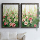 Set of two black barnwood framed canvas prints depicting loose blossoms, green stems, and sunlit watercolor texture arranged across two complementary compositions above a sofa in a bright living space.