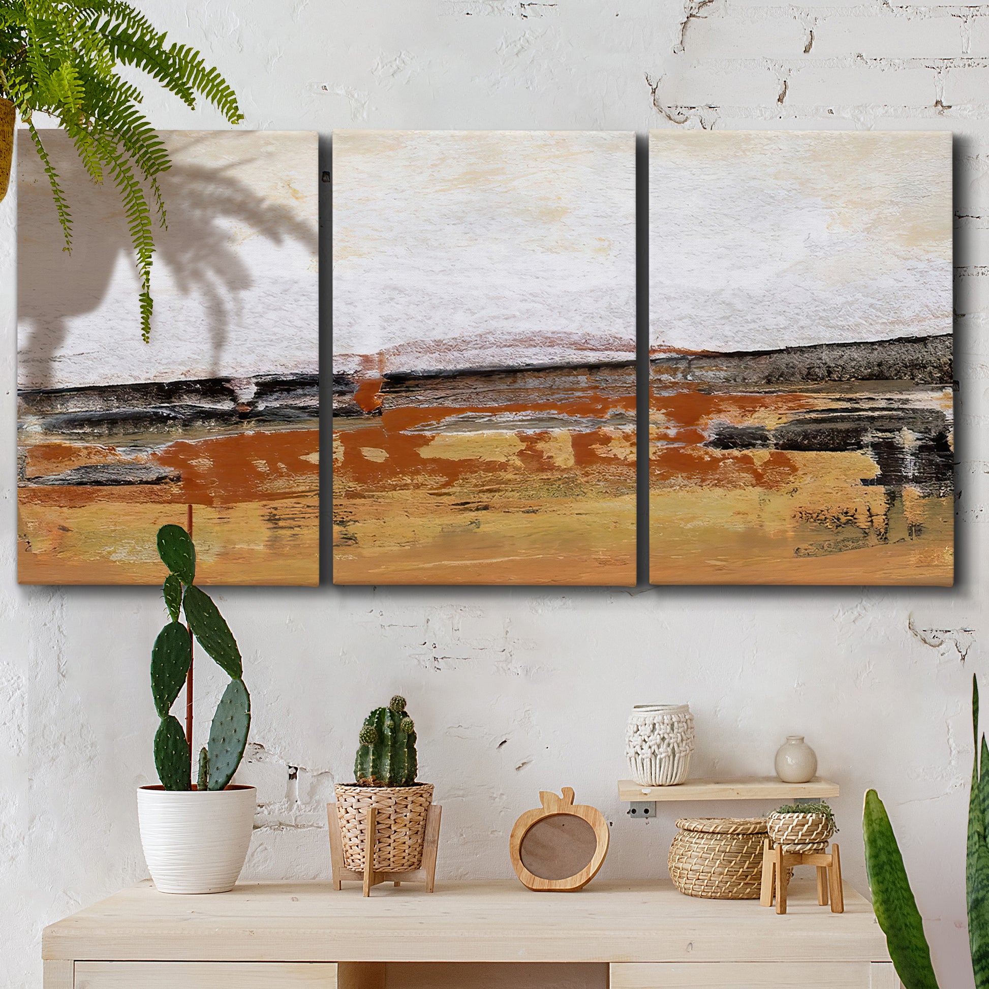 Three-panel canvas wall art featuring abstract bridge landscape in ochre, displayed in a boho-chic entryway above a console table.