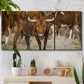 Three-panel canvas wall art featuring longhorn cattle standing together, displayed in a boho-chic entryway above a console table.