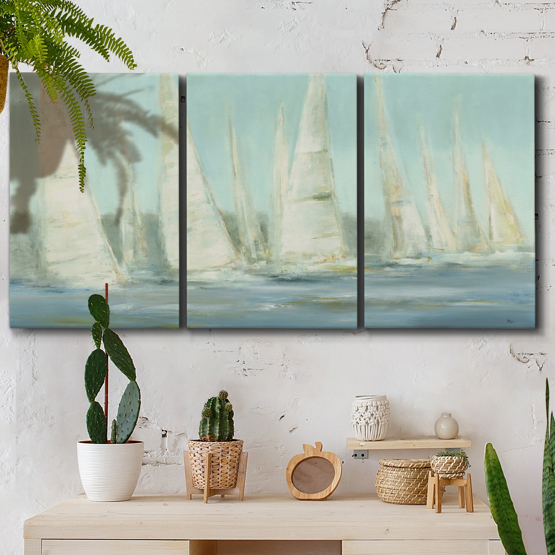 Three-panel canvas wall art featuring sailboats silhouetted at sunrise, displayed in a boho-chic entryway above a console table.