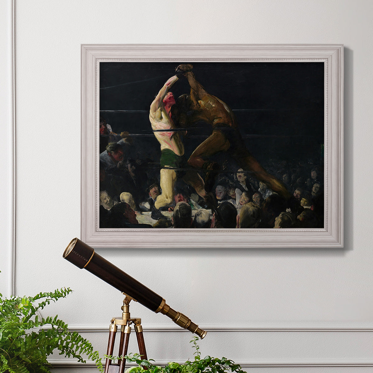 American genre painting of men in a social club by George Bellows in an ornate weathered white frame displayed in a light-toned interior setting.