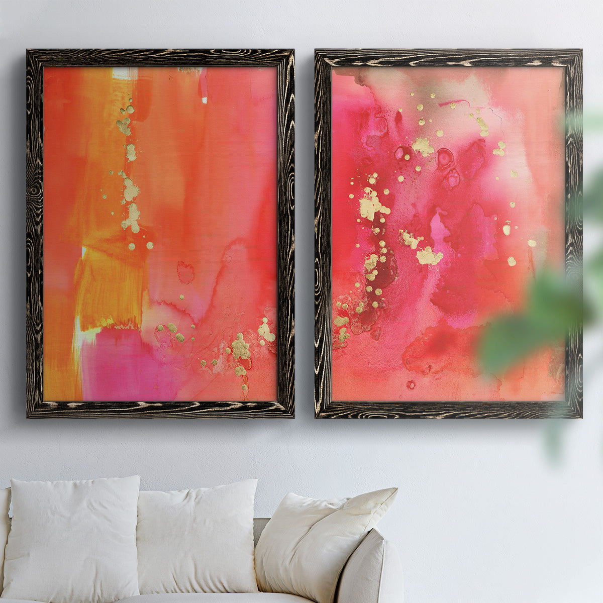 Set of two black barnwood framed canvas prints depicting translucent warm washes, drips, and scattered metallic accents arranged across two complementary compositions above a sofa in a bright living space.