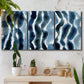 Three-panel canvas wall art featuring flowing blue watercolor wave forms, displayed in a boho-chic entryway above a console table.