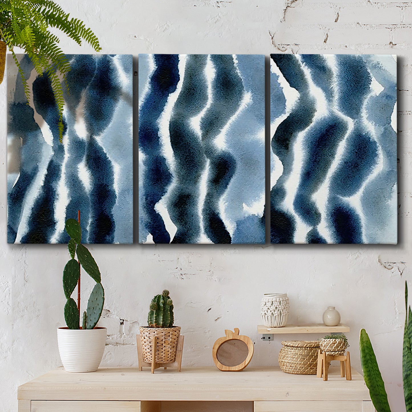 Three-panel canvas wall art featuring flowing blue watercolor wave forms, displayed in a boho-chic entryway above a console table.