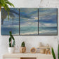 Three-panel canvas wall art featuring sunbeams breaking through coastal clouds, displayed in a boho-chic entryway above a console table.